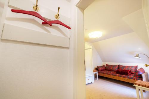 a living room with a couch and red shoes hanging on the wall at Haus Süderende in Keitum