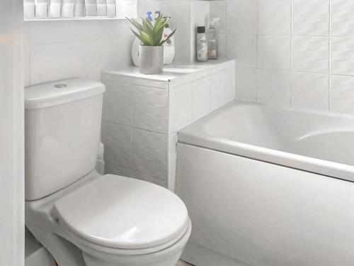 a white bathroom with a toilet and a bath tub at The Gainsborough Mews in Gainsborough