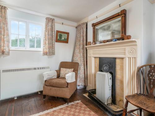 a living room with a fireplace and a chair at Gore Cottage in Powerstock