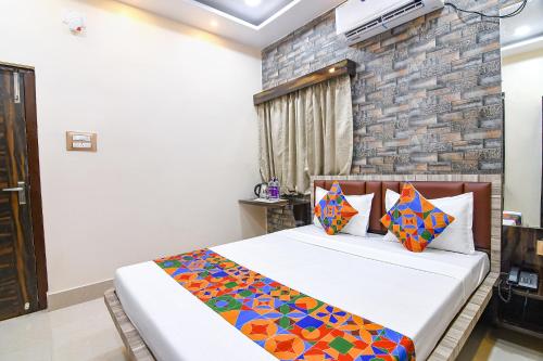 a bedroom with a bed and a brick wall at FabHotel Sriya in Durgāpur
