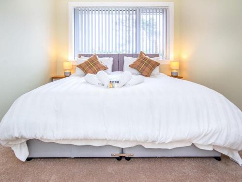 1 dormitorio con 1 cama blanca grande y ventana en Colbheinn Cottage, en Brora