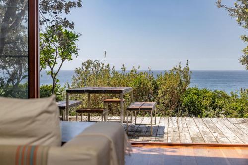 a patio with a table and chairs and the ocean at Barefoot on Blueys in Blueys Beach