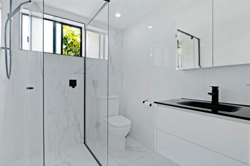 a white bathroom with a glass shower and a sink at Tranquil Scape-Villa with Pool by Gold Coast Premium in Gold Coast