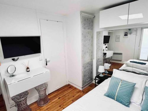 - une chambre blanche avec un lit et une télévision murale dans l'établissement Iconic location only 500 meters to The Louvre, à Paris