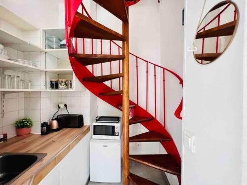 a red spiral staircase in a kitchen with a counter at Iconic location only 500 meters to The Louvre in Paris