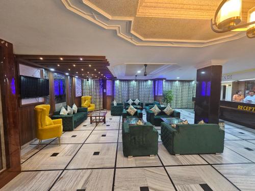 - un hall avec des canapés verts et des chaises jaunes dans l'établissement Hotel Bhawani International, à Katra