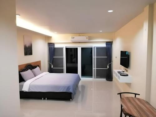 Triple J Hometel في شاطئ بانغ تاو: غرفة نوم بسرير ابيض وتلفزيون