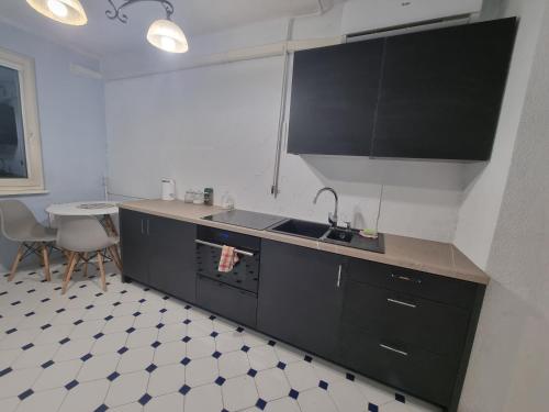 a kitchen with black cabinets and a sink and a table at Korczaka Skyline in Elblag