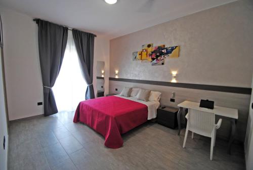 una camera d'albergo con letto rosso e tavolo di Novo Motel a Tortoreto