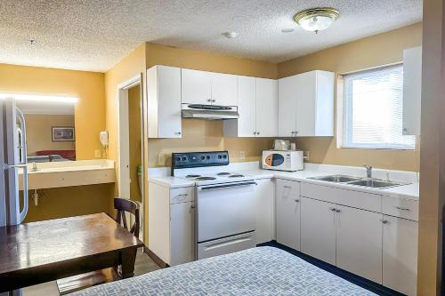 a kitchen with white cabinets and a sink and a table at Garden Inn & Suites in Rome
