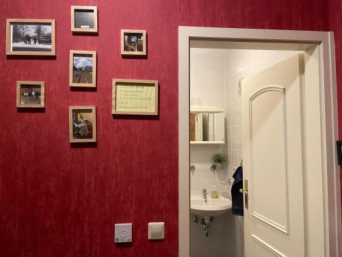 a bathroom with a red wall with pictures on it at Pension Grasse Hofladen Cafe GenießerImbiss Kehrigk in Kehrigk