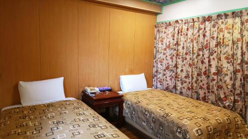 a room with two beds and a curtain at Longchi Hot-Spring Hotel in Jiaoxi