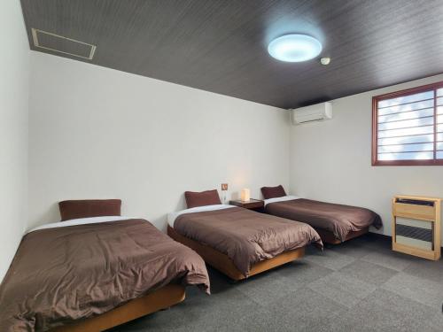 a bedroom with two beds and a tv and a window at Pension Kobekko in Otari