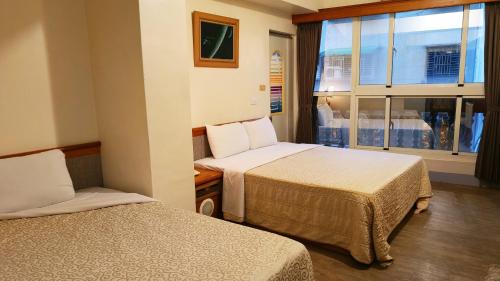 a hotel room with two beds and a window at Longchi Hot-Spring Hotel in Jiaoxi