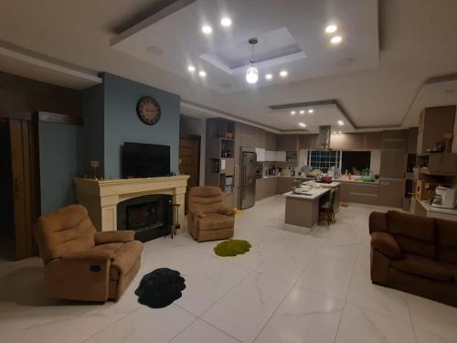 a living room with a fireplace and chairs and a kitchen at The Oaks in Madaba