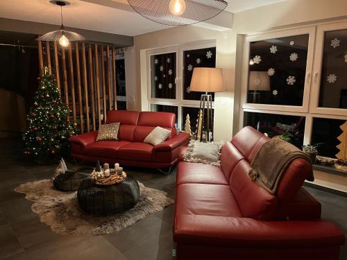 a living room with a red couch and a christmas tree at Maison d hotes Coeur de Village Alsace & spa in Rohrwiller