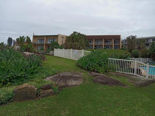 einen Hof mit einem weißen Zaun und einem Gebäude in der Unterkunft Glenmore Sands Beach Resort in Port Edward
