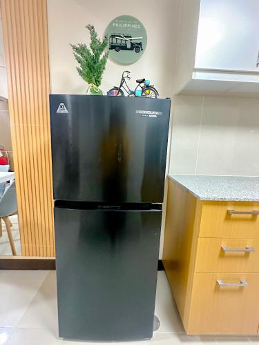 a black refrigerator with a plant on top of it at 1BR BGC Uptown Modern Condo Netflix 200Mb Wifi in Manila