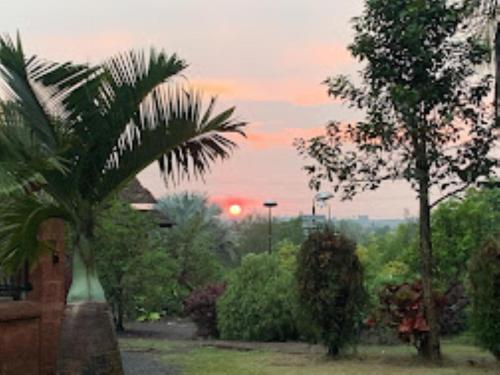 einen Sonnenuntergang in einem Park mit Bäumen und Sträuchern in der Unterkunft Heritage Resort , Kolhapur in Kolhapur