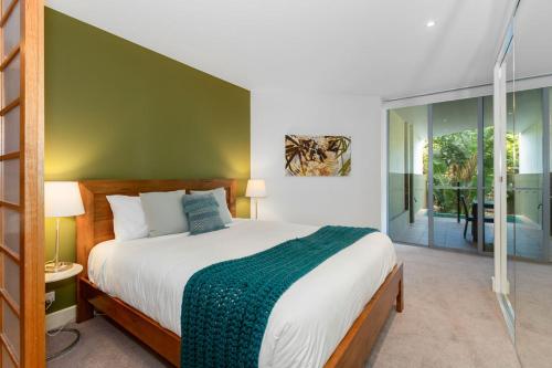 a bedroom with a large bed with a green wall at Cotton Beach Resort - Holiday Management in Kingscliff