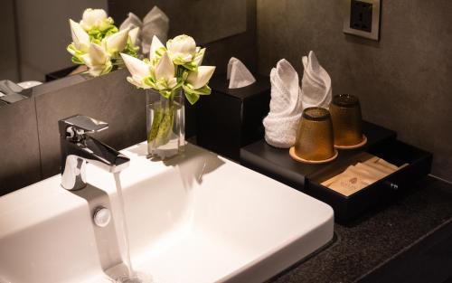 a bathroom with a sink and a vase of flowers at Koulen Central Hotel in Siem Reap