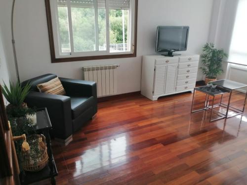 a living room with a couch and a tv at Alojamiento Santa Maria Bertamirans II in Ortoño