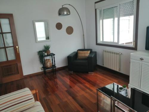 a living room with a black chair and wooden floors at Alojamiento Santa Maria Bertamirans II in Ortoño