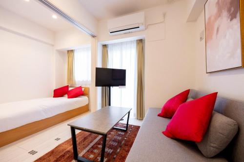 a room with a bed and a couch and a table at Noble Park KINSHICHO in Tokyo