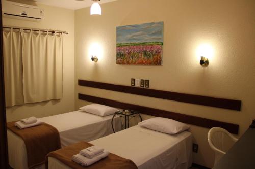 um quarto com duas camas e um quadro na parede em Hotel Santa Rita em Indaiatuba