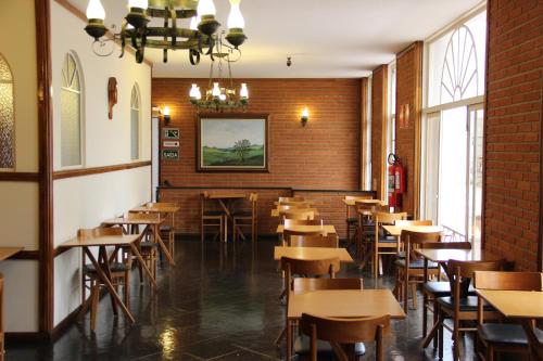 uma sala de jantar com mesas e cadeiras de madeira em Hotel Santa Rita em Indaiatuba