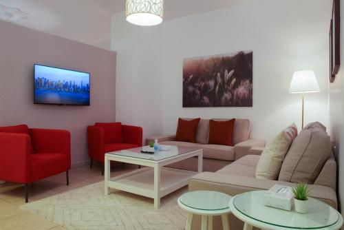 a living room with a couch and two red chairs at Toledo Amman Hotel in Amman