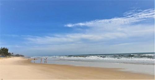 a beach with people walking on the sand and the ocean at TTC Resort Ke Ga in Ke Ga