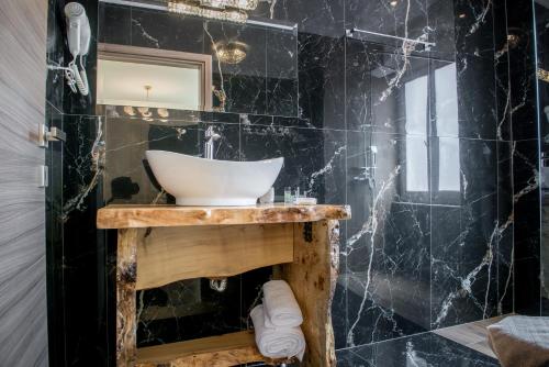 a bathroom with a sink and a black wall at Oniro PargaTown Luxury Suites in Parga