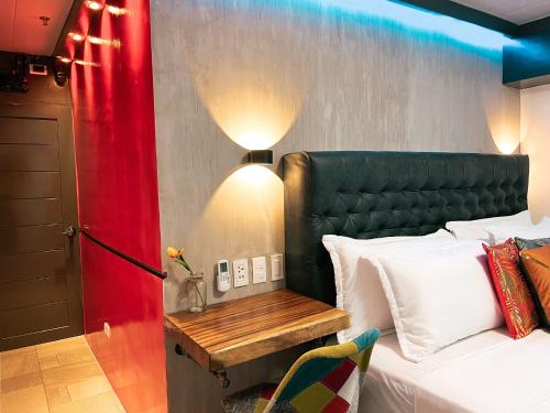 Schlafzimmer mit einem Bett mit einem grünen Kopfteil und einem Tisch in der Unterkunft CLOCKWORKORANGE Luxury Suites 4-Minutes Away To Airport in Mactan
