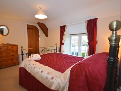 3 Bed in Lyme Regis BARRA في Winsham: غرفة نوم بسرير لحاف احمر ونافذة