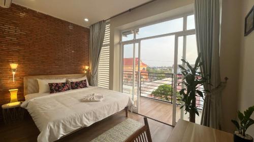 um quarto com uma cama e uma grande janela em Cambodhi - Vegan Guesthouse em Kampot