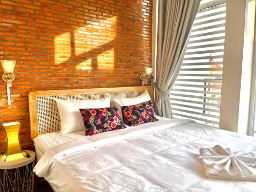 a bedroom with a white bed and a brick wall at Cambodhi - Vegan Guesthouse in Kampot