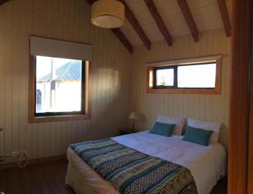 1 dormitorio con 1 cama y 2 ventanas en La Cascada Duplex en San Martín de los Andes