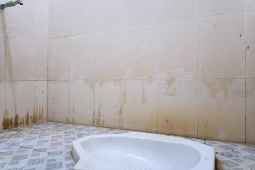 a dirty bathroom with a tub in the corner at OYO 93435 Yuda Family Homestay in Lembuak