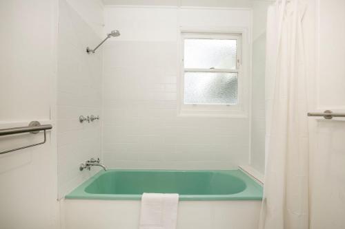 a bath tub in a white bathroom with a window at Jack's Culburra - Absolute Waterfront with Fireplace in Culburra Beach