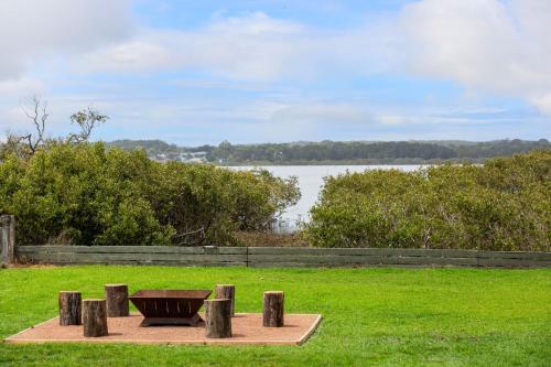 a bench in the grass next to a body of water at Jack's Culburra - Absolute Waterfront with Fireplace in Culburra Beach