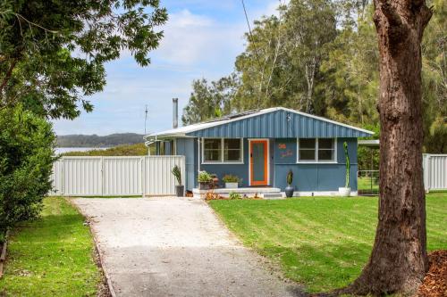 a blue house with an orange door in a yard at Jack's Culburra - Absolute Waterfront with Fireplace in Culburra Beach