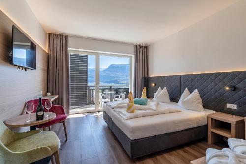 テルメーノにあるHotel Winzerhofのベッドと大きな窓が備わるホテルルームです。