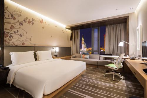 a hotel room with a large bed and a desk at Hilton Garden Inn Ningbo in Ningbo
