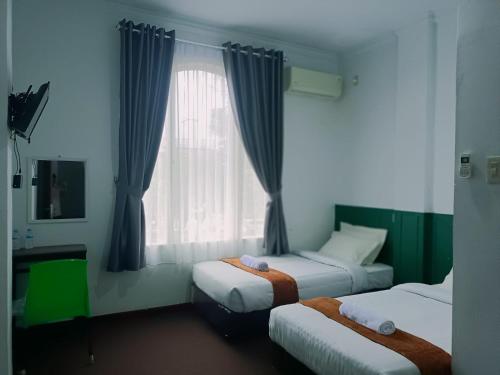 a bedroom with two beds and a window at Quanza Hotel in Banda Aceh