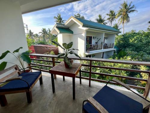 a balcony with a table and chairs and a house at Fat Lips Surf Lodge in General Luna