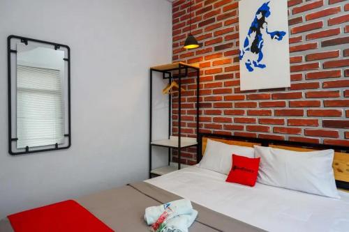 Un dormitorio con una pared de ladrillo y una cama en RedDoorz near Universitas Muhammadiyah Purwokerto 2, en Kembaran