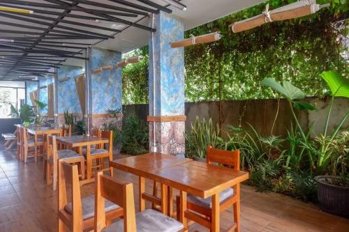 un restaurant avec des tables en bois, des chaises et des plantes dans l'établissement RedDoorz near Universitas Muhammadiyah Purwokerto 2, à Kembaran