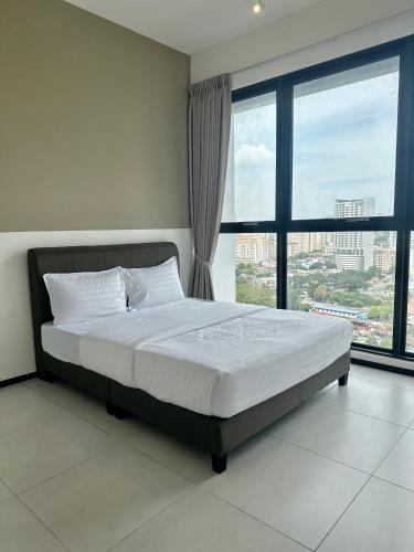 a bed in a bedroom with a large window at Urban Suites Georgetown by BNB4U in Jelutong