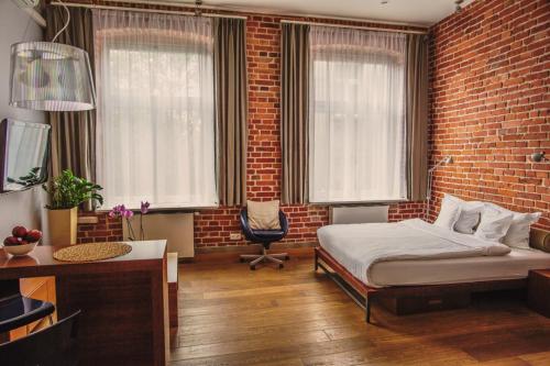 a bedroom with a bed and a brick wall at Apartamenty Straszewskiego in Krakow